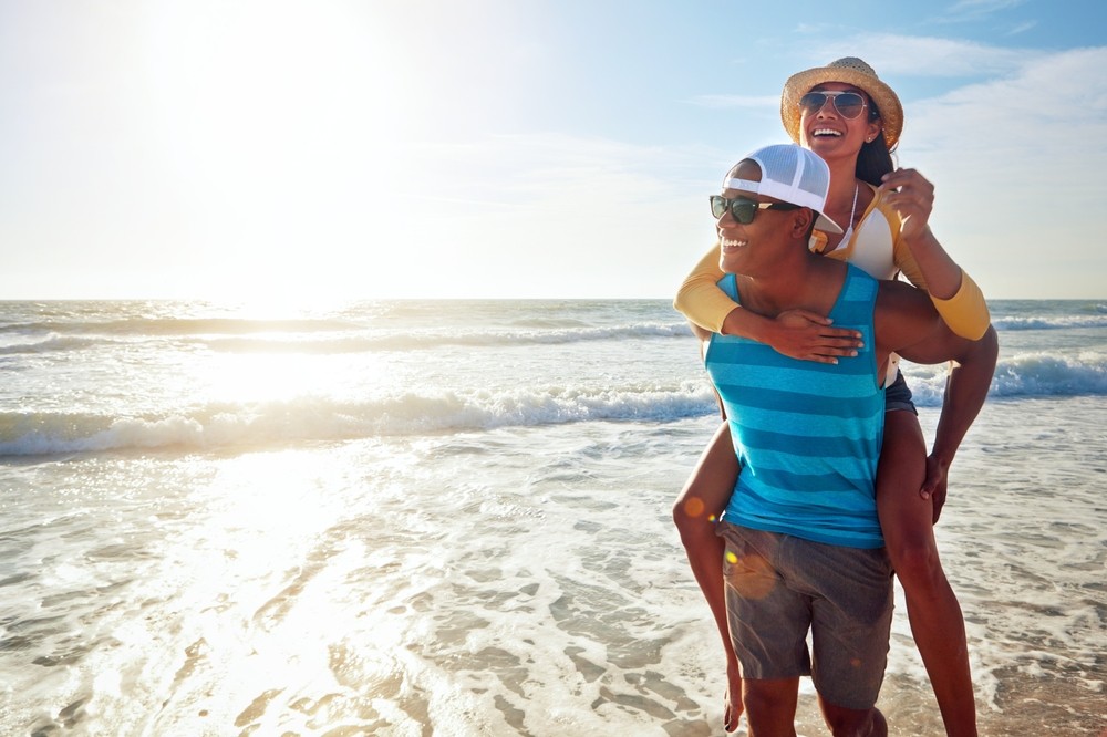 a happy, smiling couple takes in the sunlight while at the beach