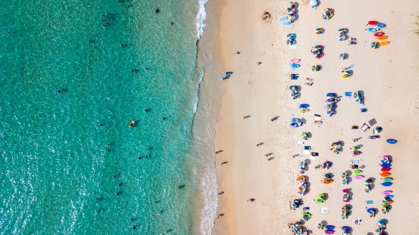 aerial view of a beach in Thailand with groups spread out under colorful umbrellas