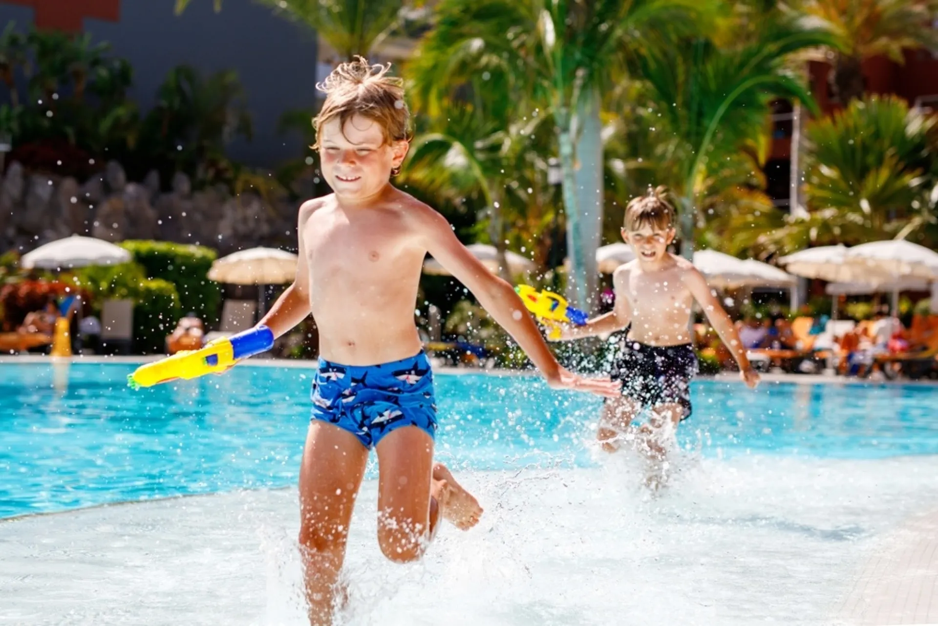 two boys play together by running through  a shallow pool